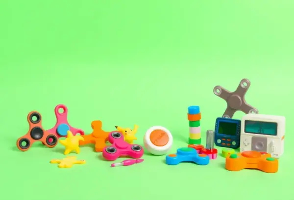 Assorted fidget spinners and 90s toys arranged colorfully on a minimalist surface.